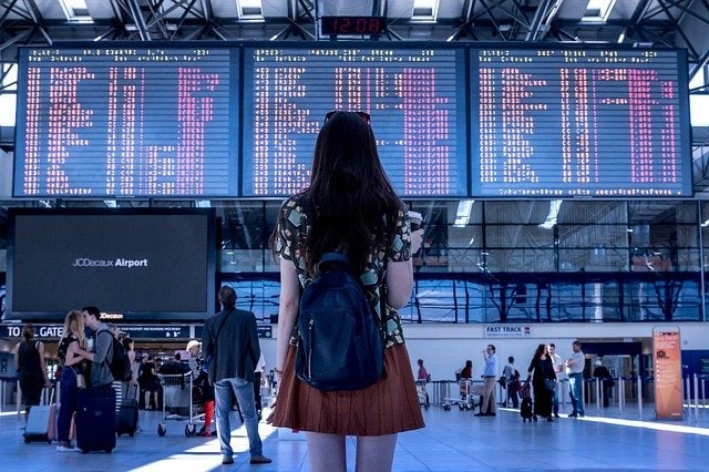 Woman standing in front of electronic arrivals board at an airport