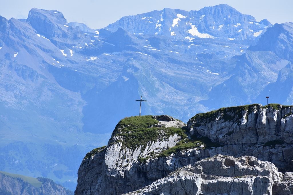 swiss alps with cross on mountain top