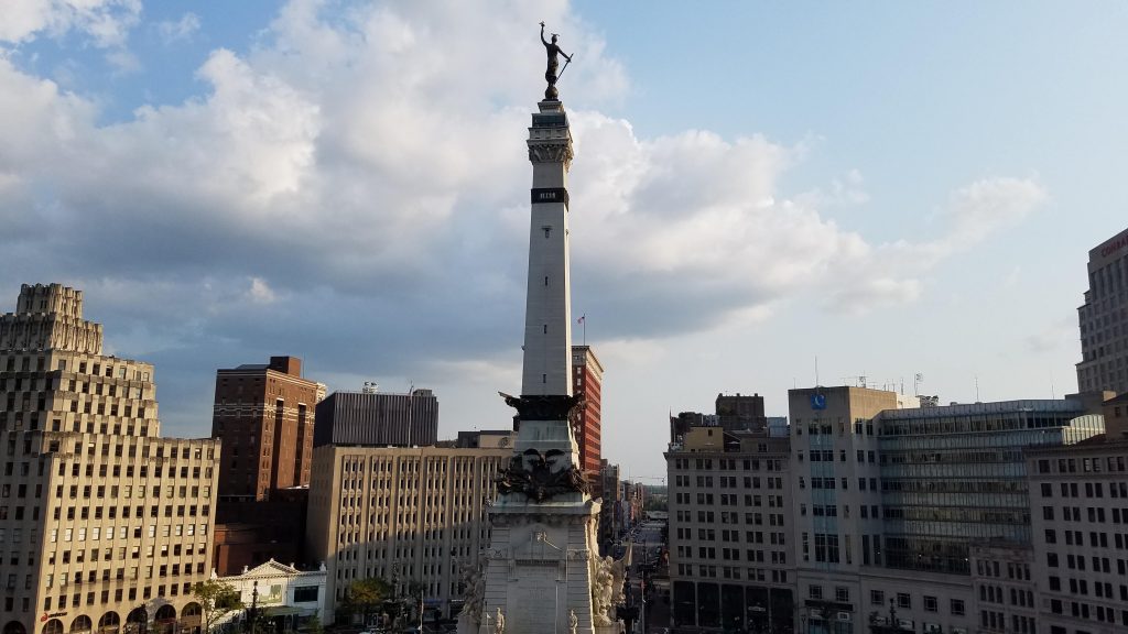 city skyline with white stone and brown bronze obelisk monument in center