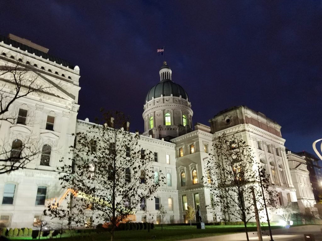 white state capitol building alight at night with dark night sky above