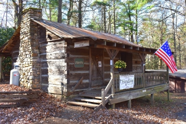 Log cabin visitor center with historic American flag waving at the Hickory Ridge History Museum in Boone, NC