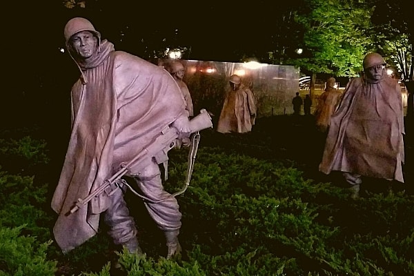 Metal statues of life-sized soldiers at the Korean War Veterans Memorial at night 