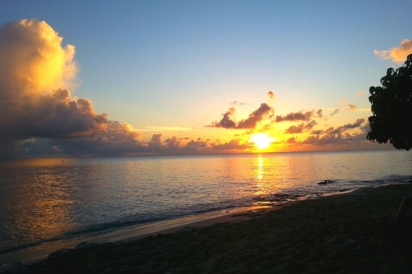 Golden orange sun setting in a still blue sky over the ocean on the west coast of St Croix near Frederiksted