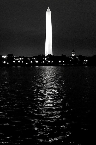 Black and white photograph of the Washington Monument at night reflected in the Tidal Basin waters