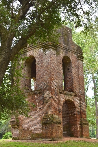 brown brick church tower ruins in a green forest