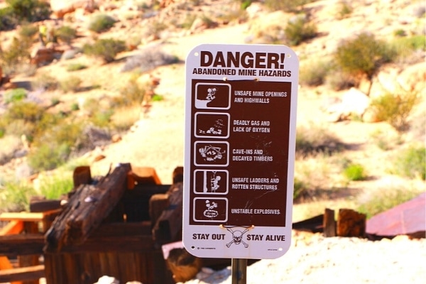 Abandoned mine danger sign in front of old mine ruins in the desert of Joshua Tree National Park