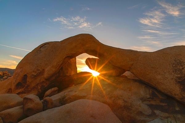 Rock arch at Joshua Tree National Park with the setting sun shining through the gap in the rocks