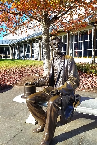 Seated bronze statue of Abraham Lincoln with his hat at his side and the Gettysburg Address in his hands, on a bench at the Gettysburg National Military Park Visitor Center