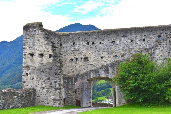 A partially ruined castle wall with original wooden gate at Gutenberg Castle in Balzers, Liechtenstein