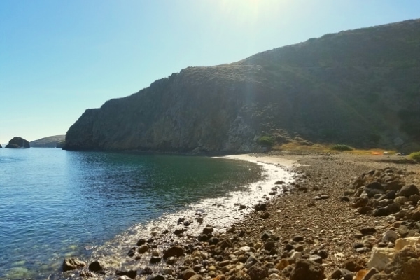 Blue green water of the Santa Barbara Channel breaks onto the rocky shore at Scorpion Ranch Anchorage, overlooked by the cliffs of Santa Cruz Island, Channel Islands, CA