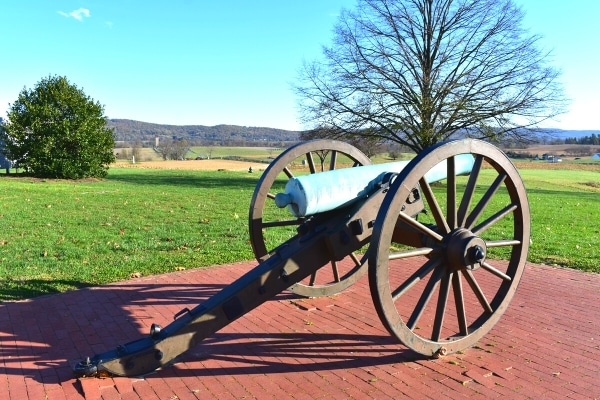 A green-patinaed cannon looks out over Antietam National Battlefield from the visitors center