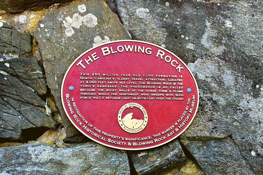 Red Historical marker placed in stone outcropping explaining the significance of the Blowing Rock