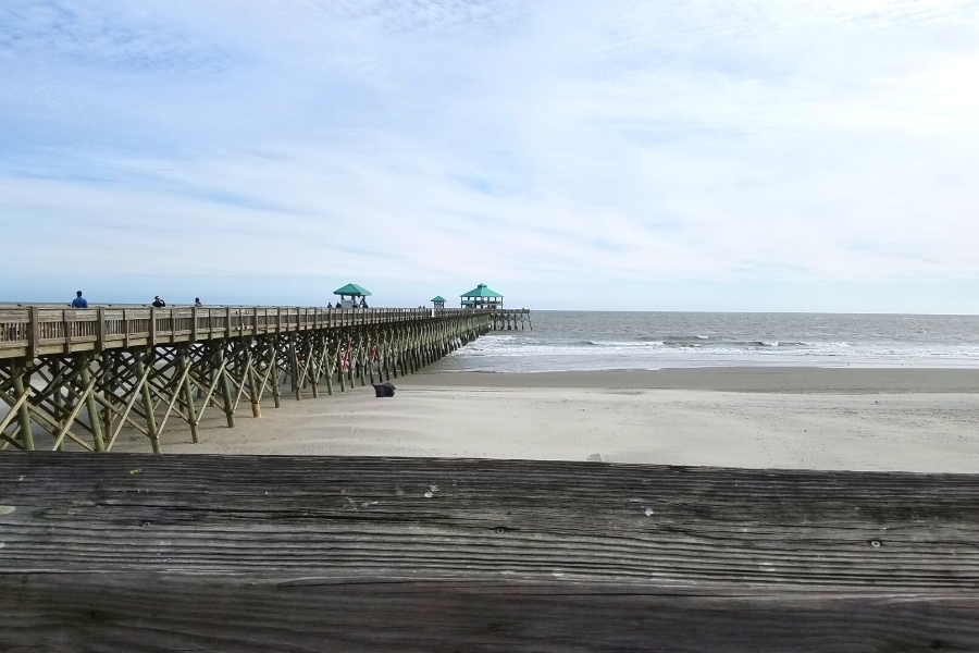 Wooden Folly Beach Pier extending across the sandy beach and into the ocean