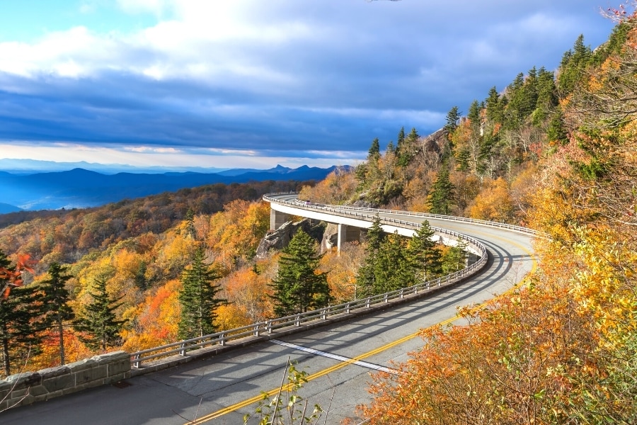 Linn Cove Viaduct on the Blue Ridge Parkway curves around the mountainside with the trees all orange for autumn