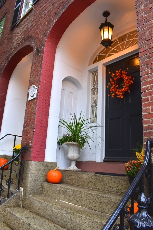 Townhome front porch in the McIntire Historic District are decorated for fall with pumpkins, mums, and an orange wreath