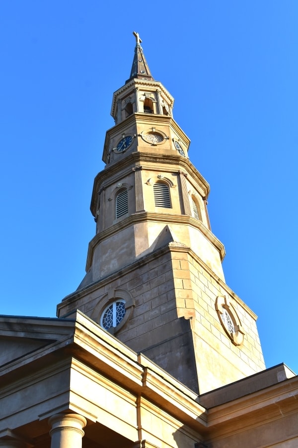 Blonde stone church spire rises up into a clear blue sky