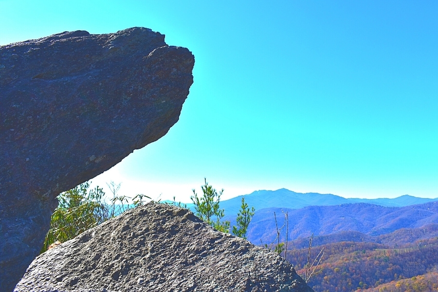 The Blowing Rock rocky outcropping hangs over a cliff with fall mountains in the background