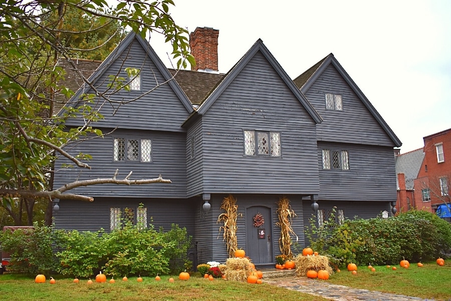 Large gray 3 story home, known as the Witch House, decorated for Halloween with pumpkins in the yard