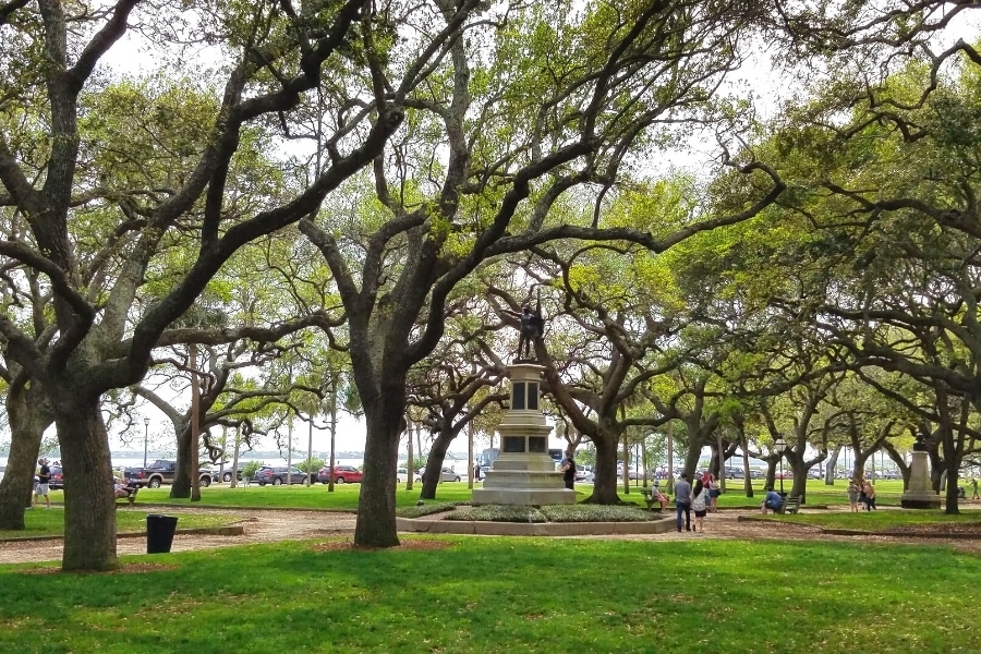 Green park full of southern live oaks with a monument in the middle