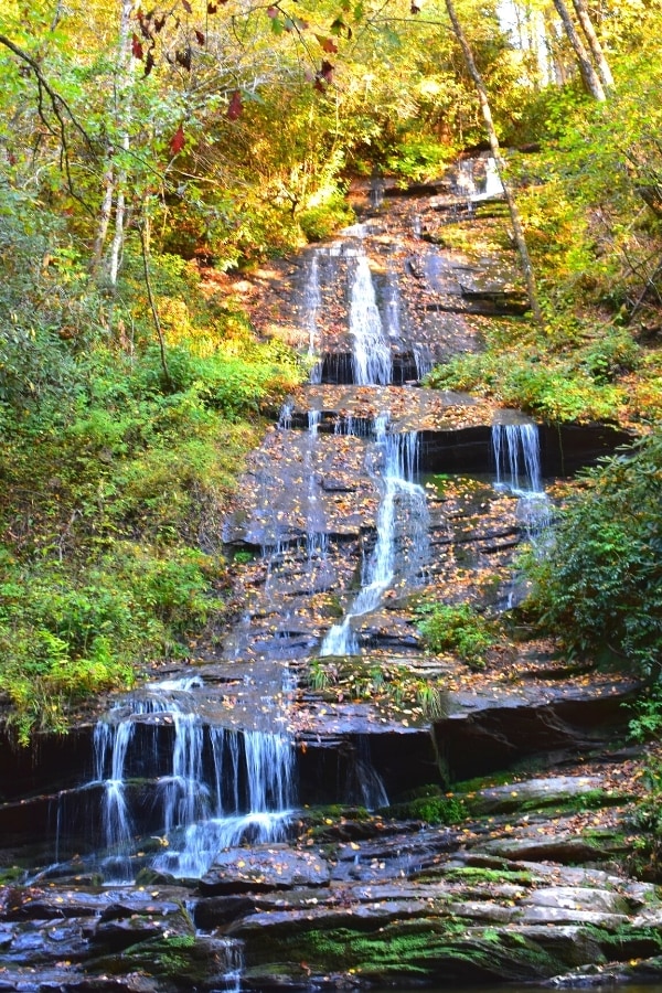 Several small trickle waterfalls of Tom Branch Falls in Great Smoky Mountains National Park falling down a rocky slope surrounded by green and yellow trees