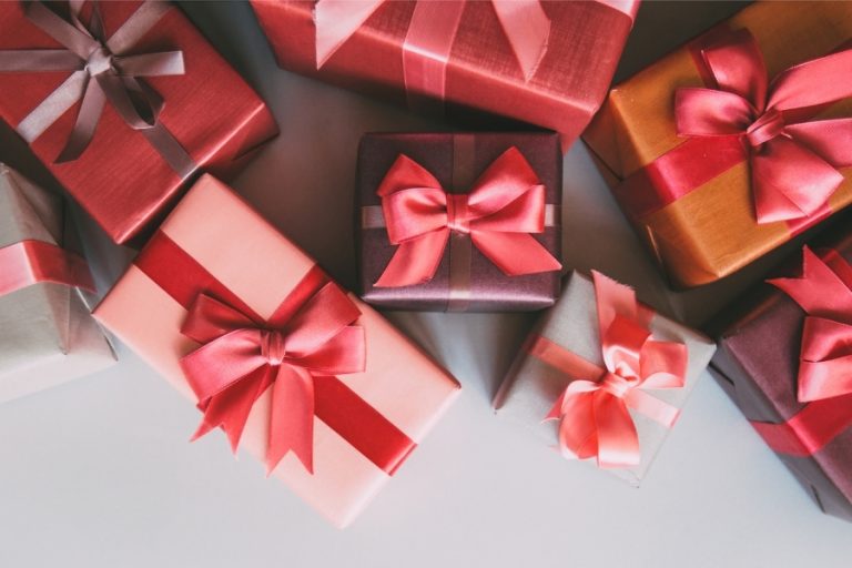 Many gift-wrapped boxes with red bows cover a white surface