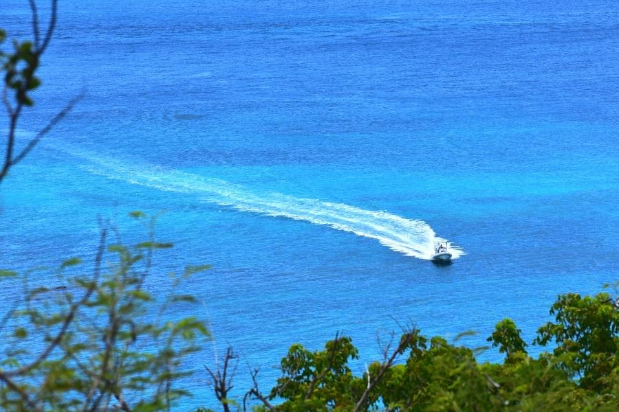 Blue water of St John, USVI with a white wake trail behind a single speed boat