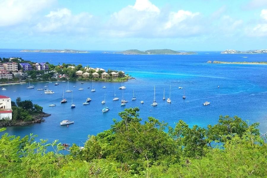 Cruz Bay of St John, USVI from above with blue waters, multiple white boats afloat, and hotels on the shore