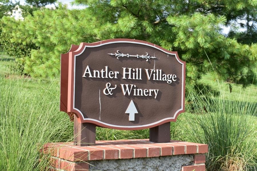 Brown sign stating "Antler Hill Village & Winery" with a straight ahead arrow