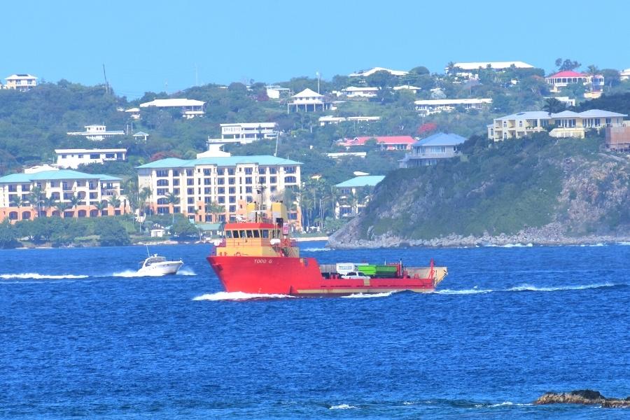 Large red car barge crosses the deep blue waters to get to St John from St Thomas, in the background