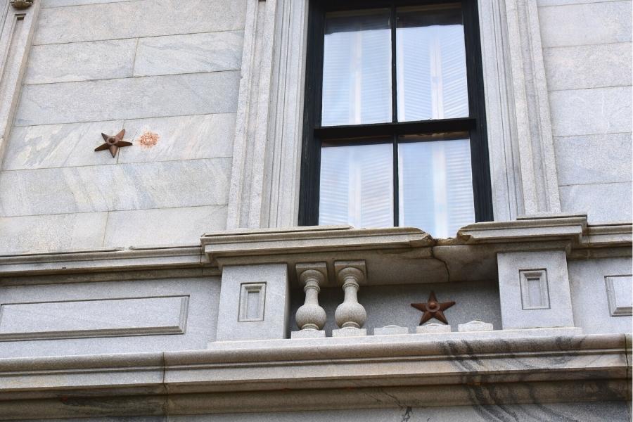 Two bronze stars mark cannonball impacts on the side of the white marble South Carolina State House in Columbia, SC