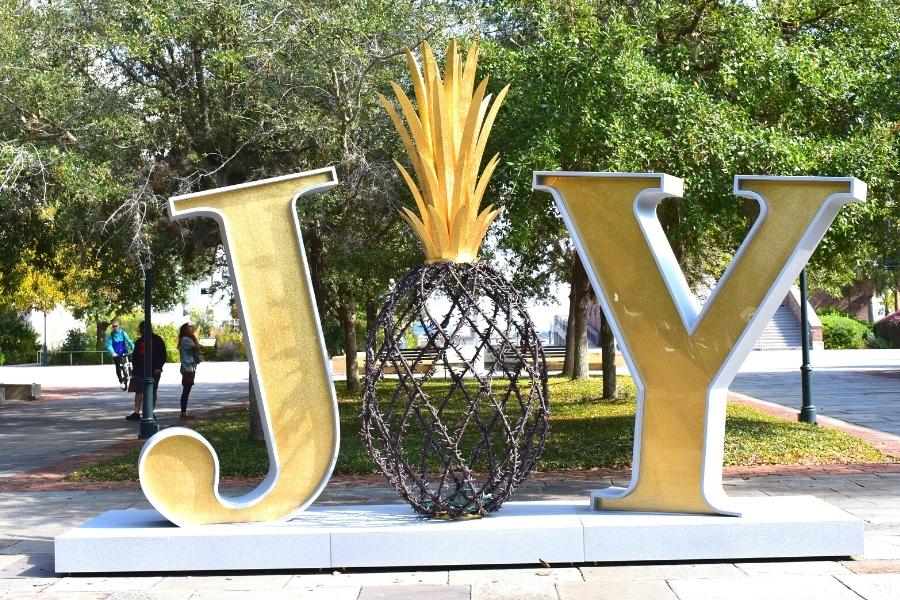 A large gold sign spells out JOY with a pineapple in place of the O