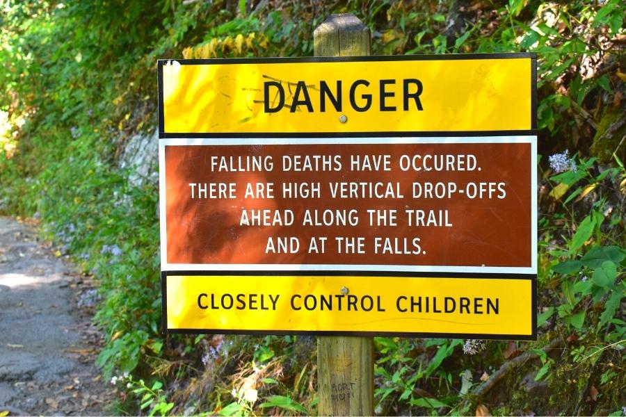 A bright yellow and brown sign warns of danger from falling from drop offs near Laurel Falls and to closely watch small children