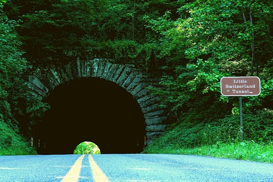 The stone arch Little Switzerland Tunnel on Blue Ridge Parkway is surrounded by green forest