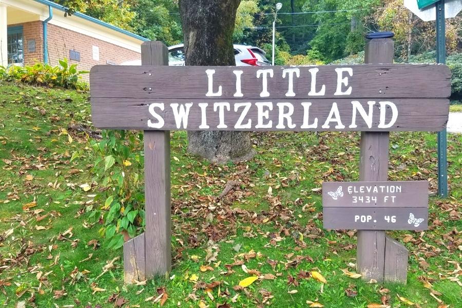 Brown wooden sign outside of the post office with the words "Little Switzerland, Elevation 3434 FT, Pop. 46"