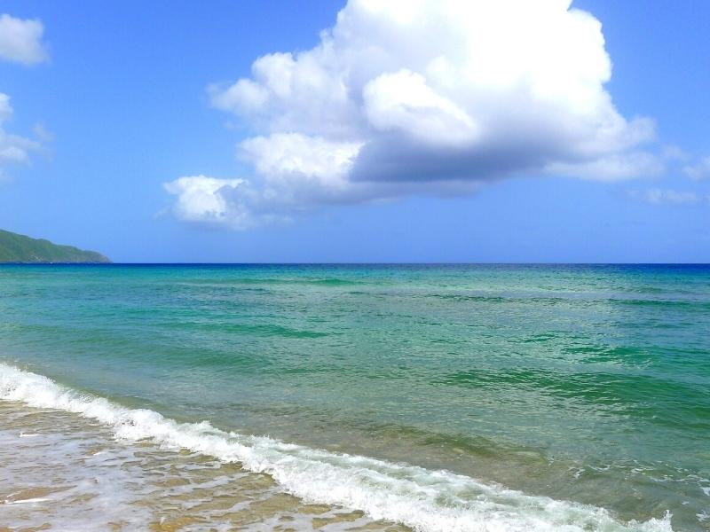 Blue-green waters of Cane Bay under a blue sky and white clouds