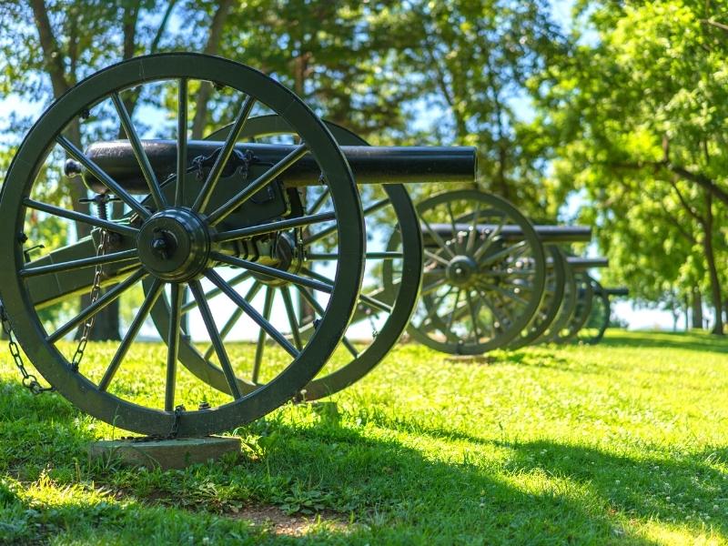 Civil War-era cannons sit in a row in a green field in Harpers Ferry National Park