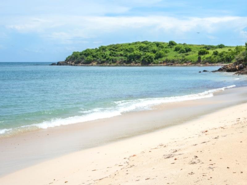 Soft sand meets blue ocean with a green hillside nearby at Cramer Park Beach on St Croix's east end