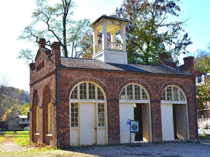 The John Brown fort is red brick and cream doors in a clearing in the Lower Town of Harpers Ferry