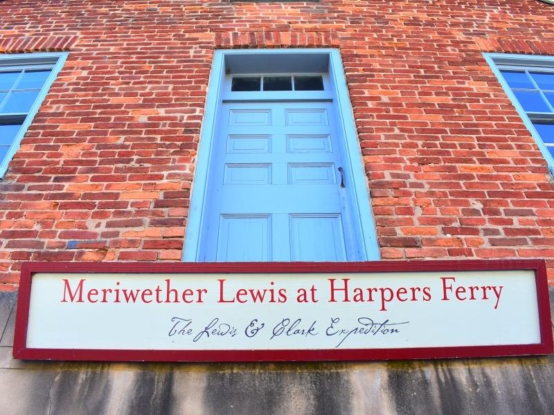 A blue door in a red brick wall, above a sign for the Meriwether Lewis shop at Harpers Ferry National Historical Park