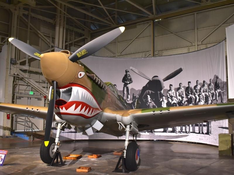 A plane with a decorative paint job snarling at visitors in an exhibit inside the Pearl Harbor Aviation Museum