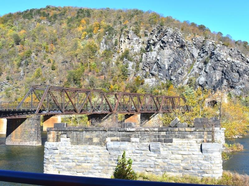 A single brown metal truss bridge remains in tact across the Potomac River at Harpers Ferry, WV