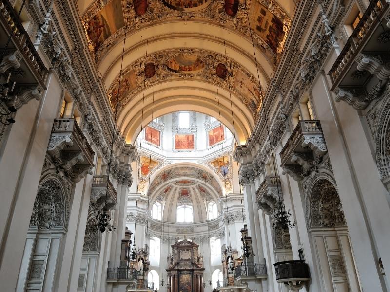 The intricate carved architectural details inside the Salzburg Cathedral nave glow slightly from late afternoon sun