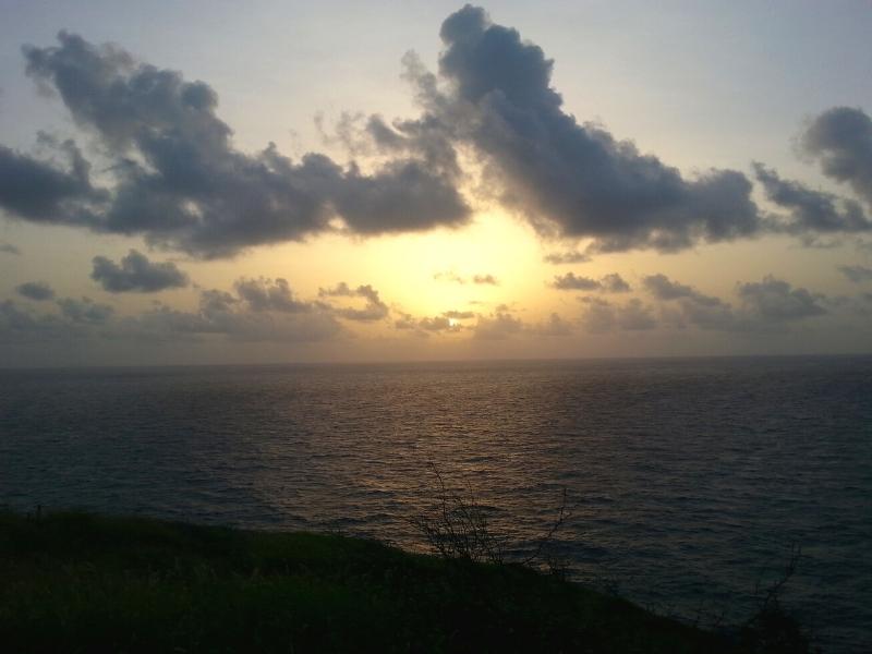 The sun rises at Point Udall St Croix with pale gold peeking through white clouds over the Atlantic Ocean
