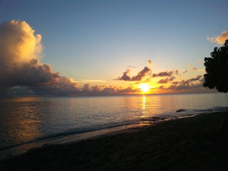 Golden sunset with large fluffy clouds and a fading blue sky over a peaceful ocean and darkened Rainbow Beach St Croix