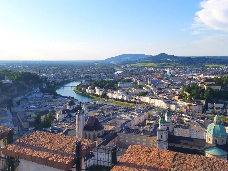 View over Salzburg, Austria with a blue sky and the sun lighting up buildings below