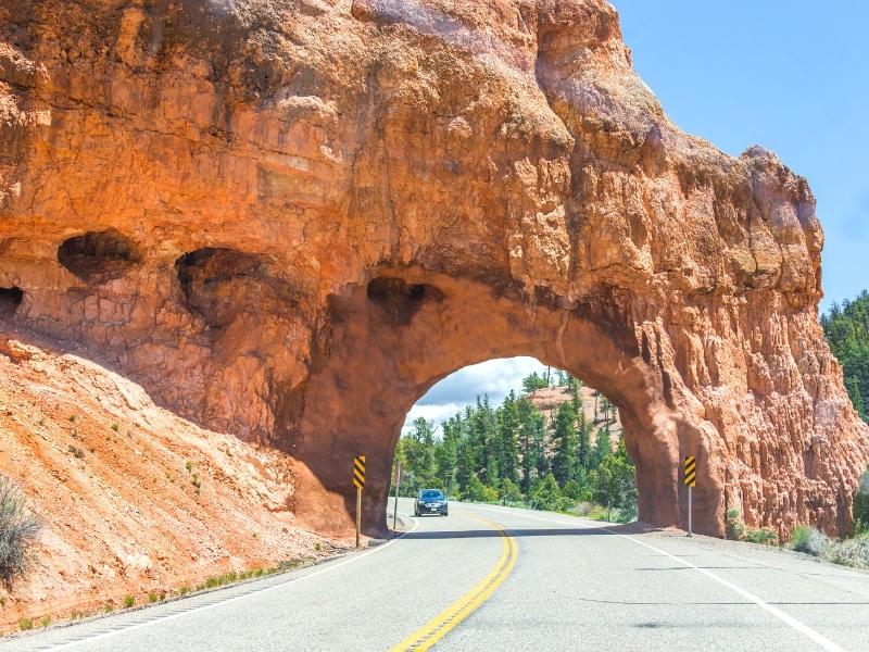 Driving down scenic State Route 12 to Bryce Canyon, cars drive through an arch in the red rocks