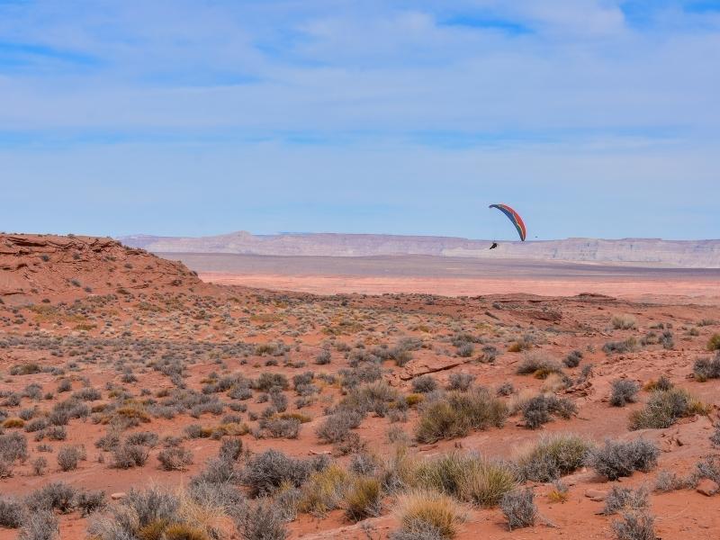 A paramotorist glides through the air above Horseshoe Bend Canyon and its surrounding desert