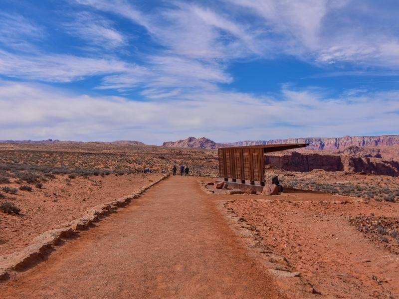 An orange patinaed steel shade structure blends in with the orange desert along the path to Horseshoe Bend Overlook