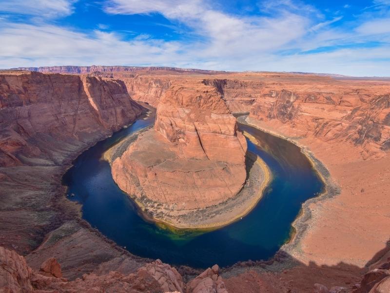 Orange canyon walls rise above the deep blue waters of the Colorado River at Horseshoe Bend, Arizona