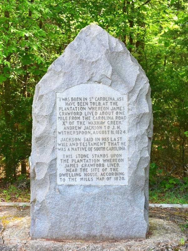 A gray stone marker, roughly chiseled around the edges and the top to a point, with clear words engraved in the middle, dedicated to Andrew Jackson